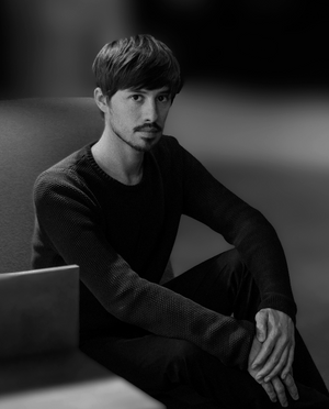 Black and white portrait of federico peri sitting on a couch.
