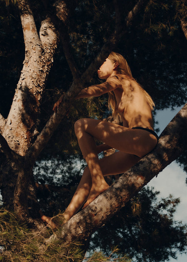 woman sitting in a pine tree with a natural background