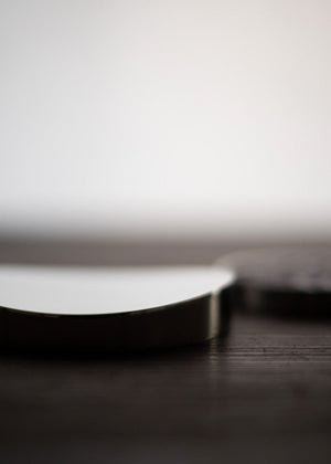 Silver food supplement container with magenta capsules on a wooden surface