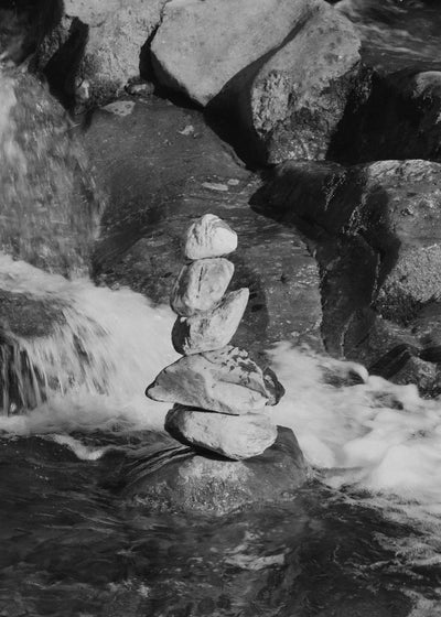 Stack of stones balanced on a rock with water flowing around