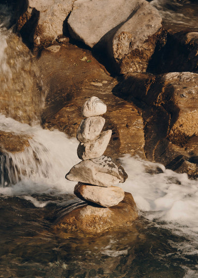 Stack of stones balanced on a rock with flowing water in the background