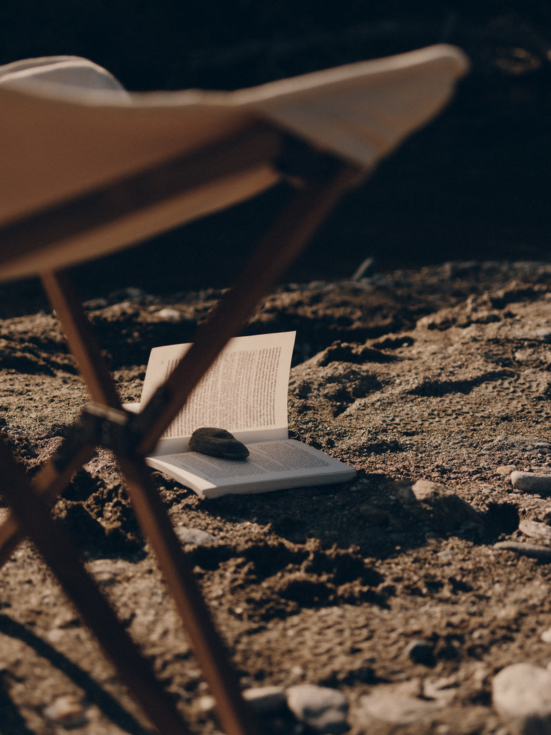 Open book on a rock with a chair in the foreground, set against a dark background