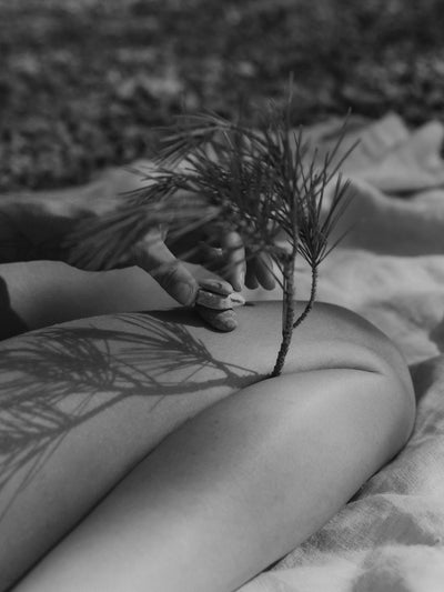 A closeup image of woman's leg sitting on a picnic rug stacking stones