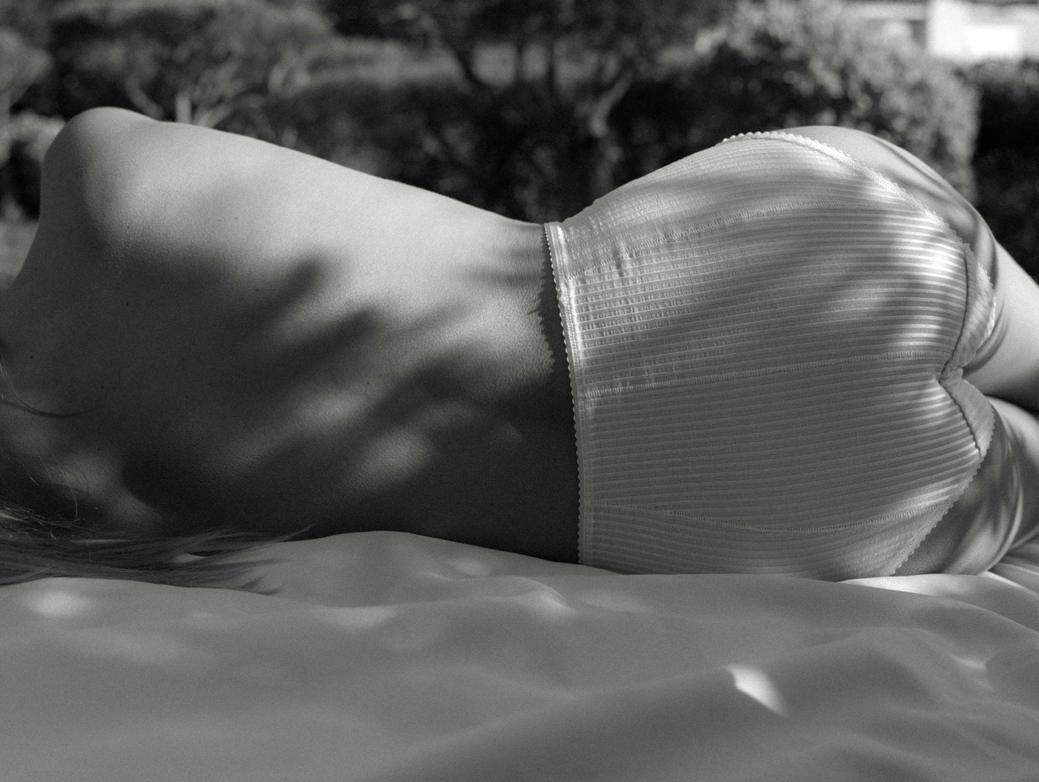 A woman lying under the shade of a tree in dappled soft natural light