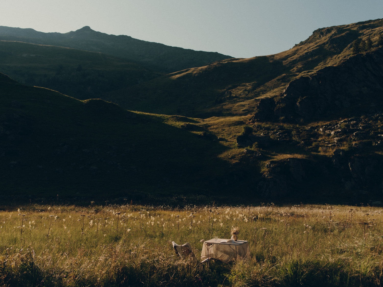A table stands alone in a field in the sun creating a sanctuary feeling.