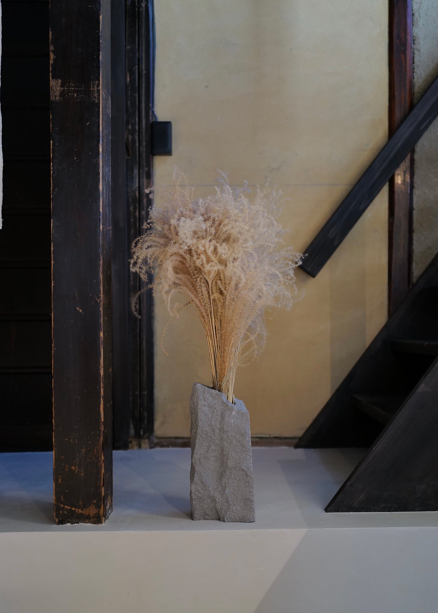 decorative vase with dried plants on a staircase at poj studio in kyoto