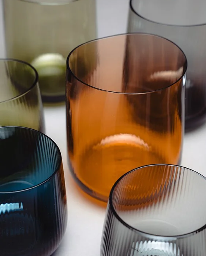 Set of colored glass tumblers on a white surface