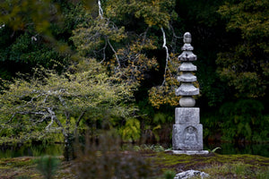 Stone pagoda in a forest setting with trees and greenery.